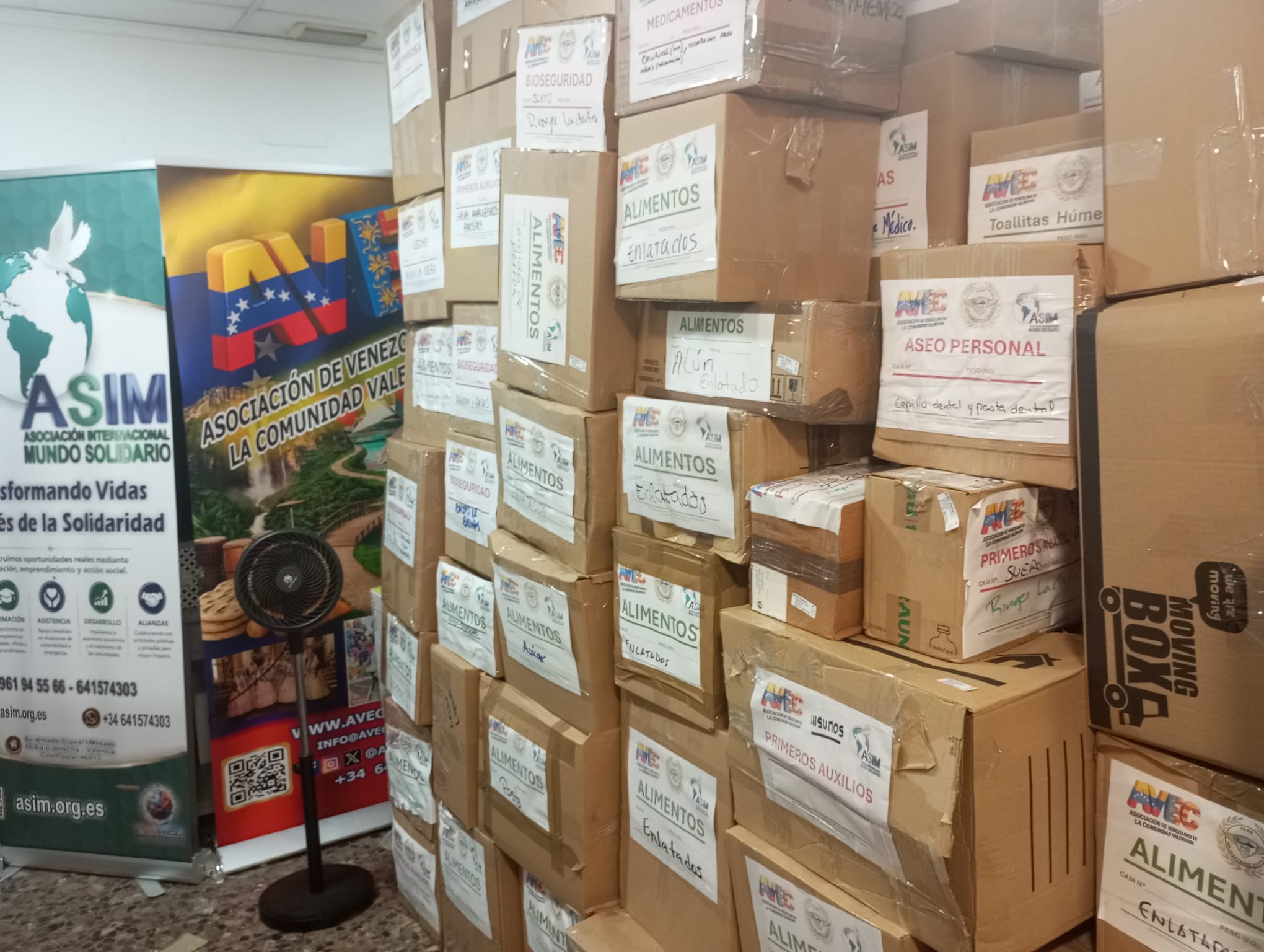 Banners de ASIM y AVEC junto a la torre de cajas de donaciones