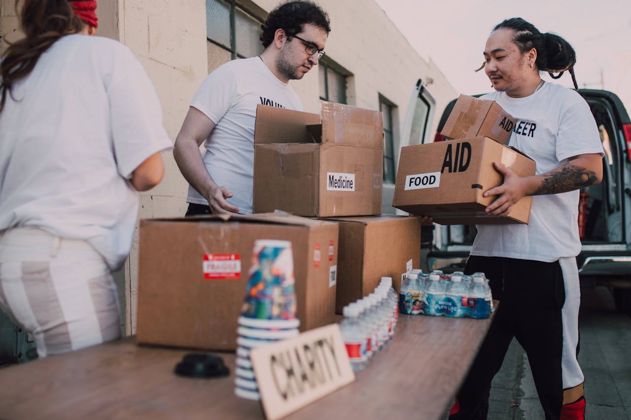 services-01 Volunteers loading aid boxes with food and medicine from a van outdoors.